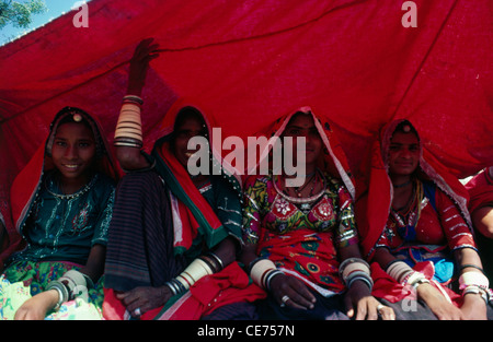 Quattro indiani donne rurali sotto la tenda rossa straccio in fiera di Pushkar Rajasthan in India Foto Stock