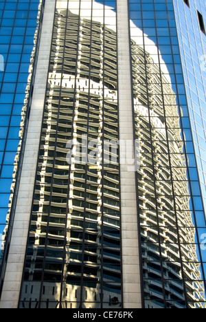 La riflessione di un grattacielo adiacente nella facciata di vetro di un edificio vicino di Sydney, Nuovo Galles del Sud, Australia Foto Stock