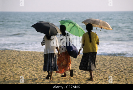 Donne locali camminando sulla spiaggia con ombrelloni, Kalutara , Sri Lanka Foto Stock
