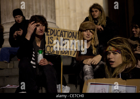 Gli studenti con un banner a leggere 'L'istruzione non è una merce" sedersi sui gradini presso il camp di occupazione al di fuori di San Paolo cathedra Foto Stock
