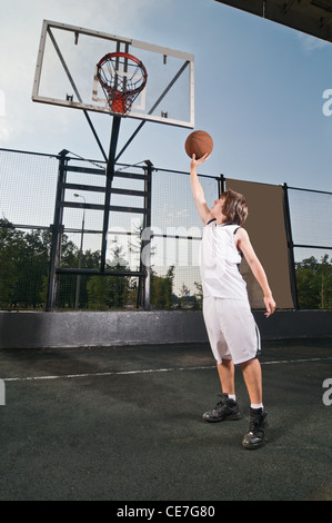 Ragazzo adolescente riprese basketball presso il parco giochi di strada Foto Stock