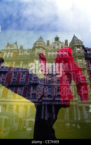 Riflesso dell'edificio in stile edoardiano del Mandarin Oriental Hyde Park in una vetrina che mostra un manichino vestito con un audace e vibrante abito rosso situato nell'area di Knightsbridge nella città di Londra nel Regno Unito Foto Stock
