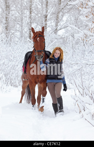 Blonde 22-anno la ragazza con il suo cavallo in un paesaggio di neve,concentrarsi sulla ragazza Foto Stock