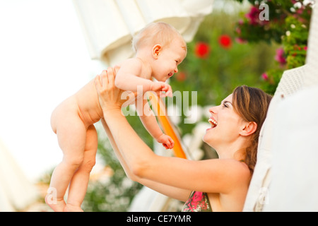 Felice giovane madre posa sul lettino e giocare con il bambino Foto Stock
