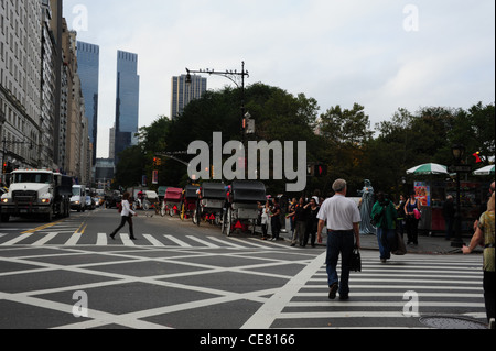 Grigio a vista cielo, guardando ad ovest, traffico, carrozze trainate da cavalli, le persone che attraversano le intersezione West 59th Street Quinta Avenue, New York Foto Stock