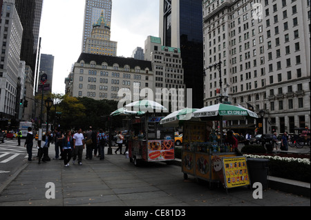 Grigio a vista cielo, verso West 59th Street grattacieli, marciapiede bancarelle che vendono gelati, hot dog, salatini, la Fifth Avenue, New York Foto Stock