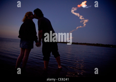 Una coppia giovane, condividere un bacio nel fiume indiano come lo space shuttle orbiter scompare dall'orizzonte, 16 marzo cape Canaveral, fla. Foto Stock