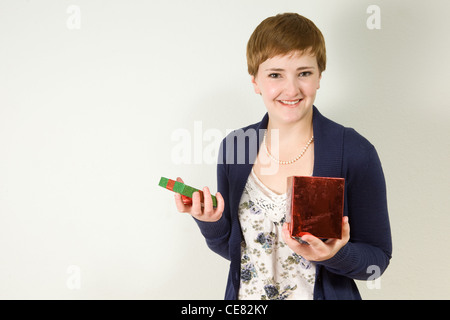 Giovani redhead white woman tenendo aperta la lamina di rosso confezione regalo. Foto Stock
