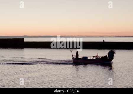 Un uomo in barca da pesca nella luce della sera,tornando al Porto di Grau d Agde,Herault,Languedoc,Francia. Foto Stock