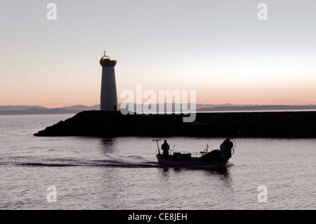 Un uomo in barca da pesca nella luce della sera, tornando al Porto di Grau d Agde, Herault, Languedoc, Francia. Foto Stock