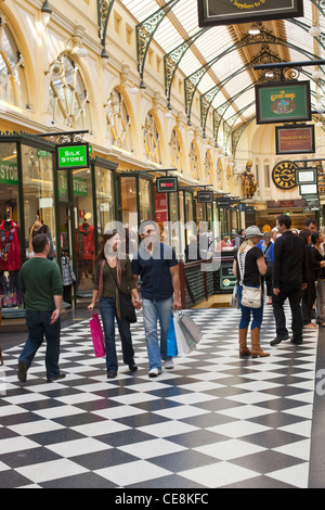 Giovane a piedi con le borse della spesa in arcade. Melbourne, Victoria, Australia Foto Stock