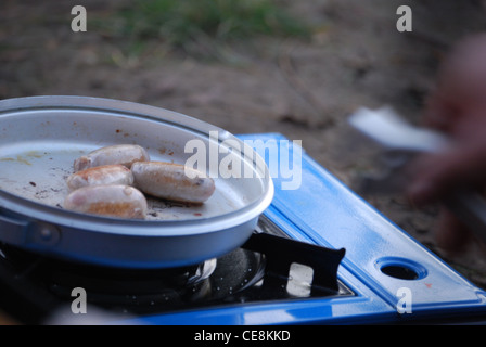 Salsicce camping cucinando fuori sulla stufa Foto Stock