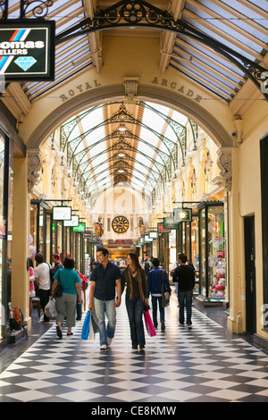 Giovane a piedi con le borse della spesa in arcade. Melbourne, Victoria, Australia Foto Stock