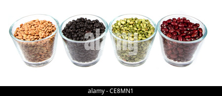 Quattro tipi di legums in contenitori di vetro, lenticchie, fagioli neri, dividere i piselli e fagioli rossi. Isolato su uno sfondo bianco Foto Stock