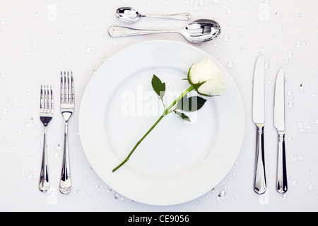 Foto di un luogo tabella di impostazione con una rosa bianca sulla piastra. Foto Stock