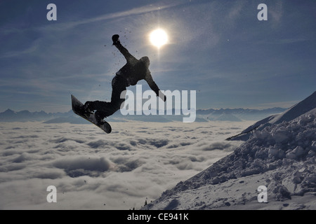 Snowboarder salta fuori una montagna contro il gocciolamento sun in tarda giornata sulla Nordkette montagna sopra Innsbruck, Austria Foto Stock