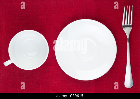 White gli utensili da cucina (CUP, la piastra forcella) su sfondo rosso Foto Stock