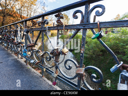 Lucchetti sul ponte di ringhiere di Vilnius, Lituania, fissato come amore gettoni - con Giallo Autunno colori in background Foto Stock