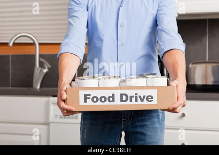 Stati Uniti d'America, Illinois, Metamora, uomo con scatola di cartone con cibo inscatolato in cucina Foto Stock