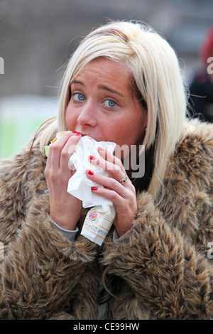 Affascinante ragazza mangiare sulla strada a sandwich Foto Stock