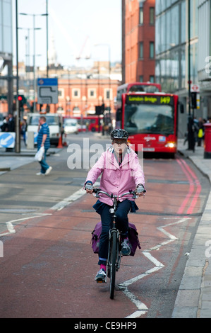 Signora in bicicletta lungo un percorso rosso nel centro della città di Londra, Inghilterra. Foto Stock