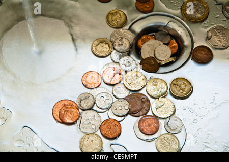 Verso il basso la scarico. Regno Unito denaro nello scarico. Monete e l'acqua nello scarico. Foto Stock