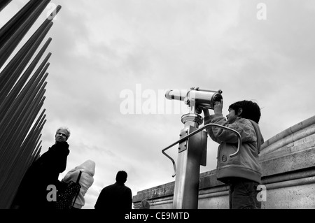 Un giovane ragazzo guardare attraverso il binocolo sulla sommità del Arc de Triomphe a Parigi Foto Stock