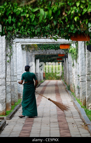 Donna indiana in abiti tradizionali spazzare il pavimento del Windflower Spa & Resort a Mysore, Karnataka, India Foto Stock
