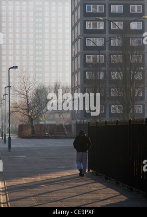 Giovane uomo a piedi attraverso Pendleton alloggiamento station wagon, centrale Salford, Greater Manchester, Inghilterra, Regno Unito Foto Stock