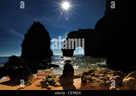 Il Portogallo, Algarve: formazioni rocciose contro la luce del sole di mezzogiorno presso la spiaggia Praia da Marinha Foto Stock