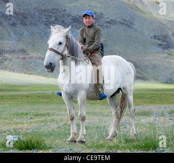 Ragazzo kazako in sella ad un cavallo bianco nelle montagne di Altai mongolo Foto Stock