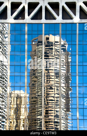 Le riflessioni della vicina città edifici nella facciata di vetro di un grattacielo adiacente Foto Stock