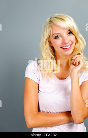 Ritratto di giovane sorridente bionda donna caucasica su sfondo grigio Foto Stock