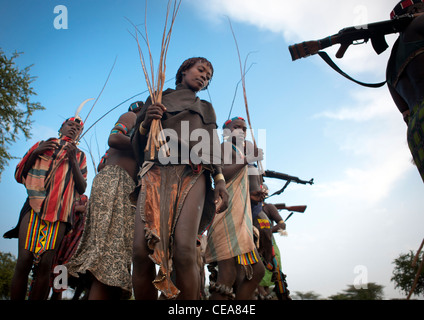 Banna le donne a piedi con fruste e Kalashnikov a Bull Jumping cerimonia Etiopia Foto Stock