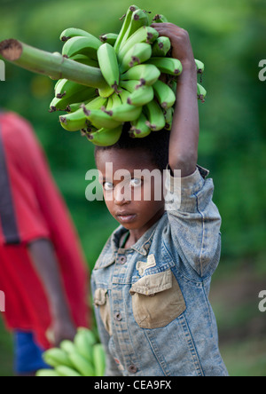 Ragazzo con banane verdi mazzetto sulla sua testa Etiopia Foto Stock