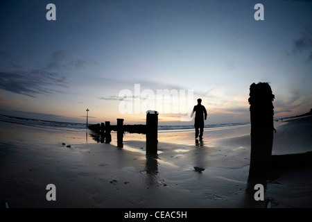 Silhouette di persona sulla spiaggia in Barmouth durante il tramonto. Foto Stock