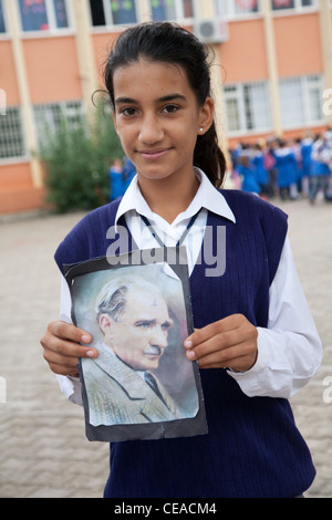 Bagno turco schoolgirl celebra la Repubblica turca giorno nella città di Tekirova, tenendo ritratto di Kemal Ataturk Foto Stock