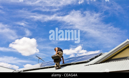 Workman installazione di energia solare dei pannelli sul tetto domestico Foto Stock