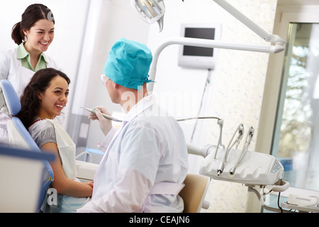 Allegro paziente che riceve cure dentarie da un medico gentile e il suo assistente Foto Stock