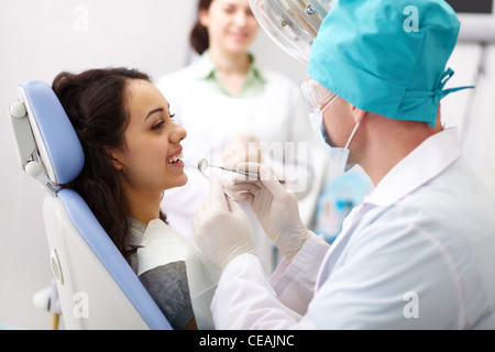 Giovani femmine paziente che riceve cure dentarie da un medico gentile e il suo assistente Foto Stock