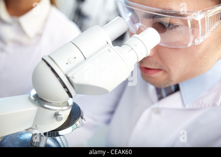 Close-up di un maschio di scienziato guardando attraverso il microscopio Foto Stock