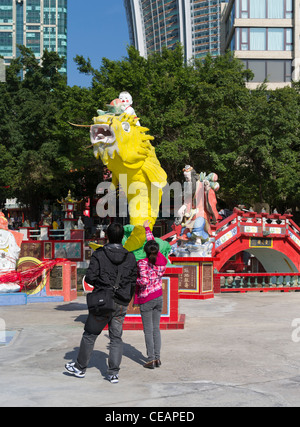 dh REPULSE BAY HONG KONG ragazza cinese e ragazzo gettando soldi in Fish of Prosperity statua bocca buona fortuna tao Foto Stock