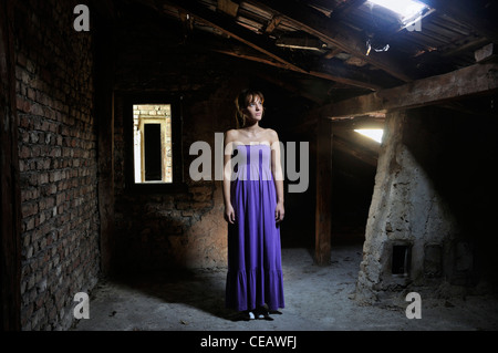 Lonely giovane donna in piedi in soffitta Foto Stock