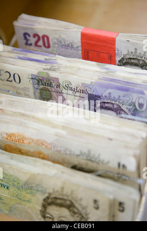 Cinque, dieci e venti pound note impilati in un contenitore Foto Stock