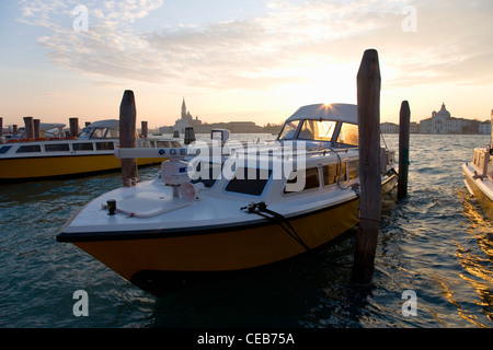 Venezia, Veneto, Italia. Barche a motore ormeggiato sul Canale della Giudecca, sunrise, Chiesa di San Giorgio Maggiore al di là. Foto Stock