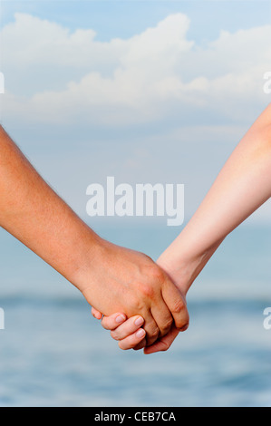 L uomo e la donna a tenere per le mani. Contro il mare e il cielo Foto Stock