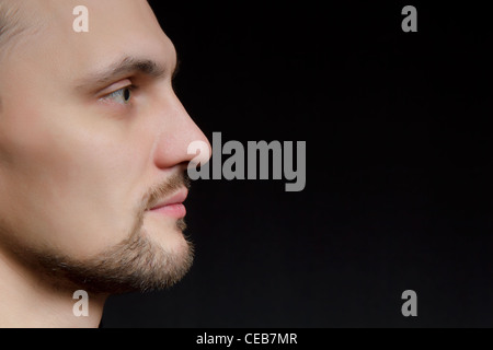 Volto del giovane uomo barba lunga in uno sfondo nero Foto Stock