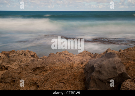Ocean di onde che si infrangono contro la costa rocciosa Foto Stock