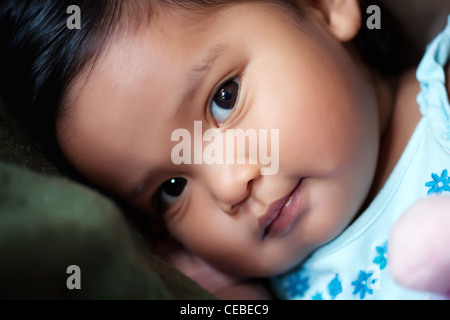 Ragazza ispanica in appoggio la sua testa su un cuscino e con un sorriso sottile Foto Stock