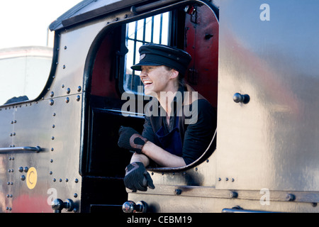 Locomotiva a vapore tirando un treno in Llangollen Railway con la femmina del driver del motore di ridere Foto Stock